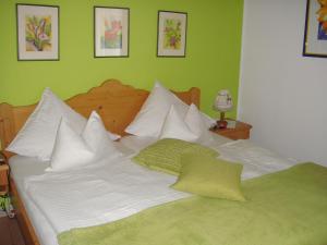 ein grünes Schlafzimmer mit einem großen Bett mit weißen Kissen in der Unterkunft Blumenpension Strauss - Ferienwohnungen in Ossiach