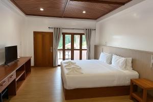a bedroom with a white bed and a television at De Hom Hotel Mae Hong Son in Mae Hong Son