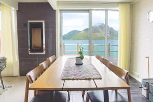 a dining room with a table and a view of the water at Modern seafront cabin with sauna 8 mins to Leknes in Storeidet