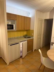 une cuisine avec des armoires en bois, un évier et une table dans l'établissement Le Papyrus -T2 Domaine Pierres et Vacances "Les Restanques du golf de Saint Tropez" à Grimaud, à Grimaud