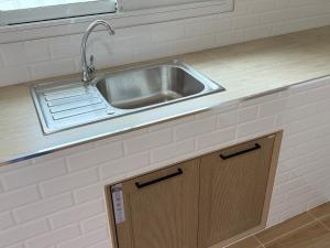 a kitchen with a sink and a wooden cabinet at เพชรไพลินรีสอร์ทสามร้อยยอด in Sathani Sam Roi Yot