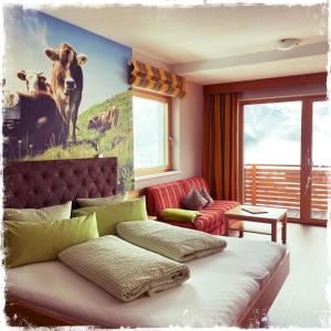 a living room with a couch and a painting of cows at Hotel Garni Alpendiamant in Fiss
