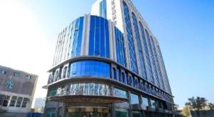 a tall glass building with a reflection of a building at Jinjiang Metropolo Hotel - Turpan Administration Center in Turfan