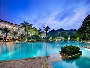 a large swimming pool with palm trees and a hotel at Dongguan MCB Lake Hotel in Dongguan