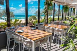 - une salle à manger avec des tables et des chaises et la plage dans l'établissement Surfers Paradise Skyline 3BR Free CP Ocean View Apartment, à Gold Coast