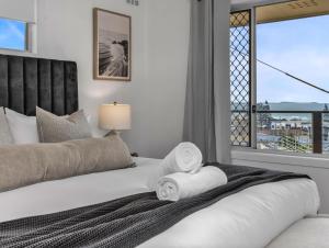 a bedroom with a bed with towels and a window at Humpback Villa in Kingscliff