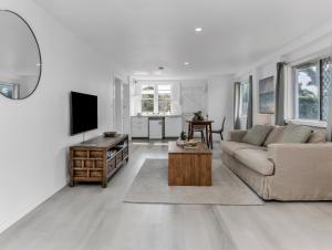 a white living room with a couch and a tv at Humpback Villa in Kingscliff