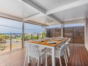 a dining room with a table and chairs on a deck at Humpback Villa in Kingscliff