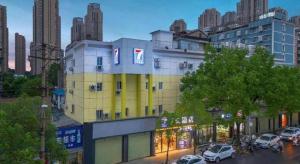 un bâtiment jaune avec des voitures garées dans une rue de la ville dans l'établissement 7 Days Inn Wuhan Dingziqiao Zhongnan Road Metro Station, à Wuhan