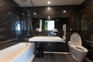 a bathroom with a sink and a toilet and a tub at Hotel Cocktail Stay Naha in Naha