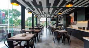a restaurant with wooden tables and chairs in a room at Zoom Dharmahusada Hotel in Surabaya