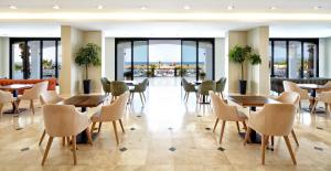 um restaurante com mesas, cadeiras e janelas em Ayvalik Cinar Hotel em Ayvalık