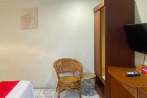 una habitación con una silla, un escritorio y un televisor en RedDoorz at Hotel Memory Batam, en Jodoh