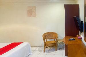 Un dormitorio con una cama y una silla y un televisor. en RedDoorz at Hotel Memory Batam, en Jodoh
