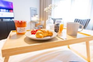 a wooden table with a plate of croissants on a table at Apartment am Schmölderpark I Klinik I Stadion I Messe I 2 Schlafzimmer I Smart TV I Küche I Balkon in Mönchengladbach +30 photos