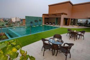a patio with tables and chairs and a swimming pool at Hotel Castle Salam in Khulna