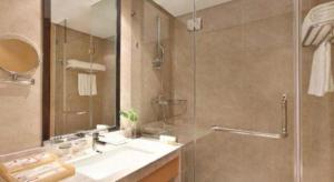 a bathroom with a shower and a sink and a mirror at Ramada Plaza by Wyndham Chuzhou in Chuzhou +95 photos