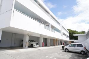 a white building with cars parked in a parking lot at ホワイトヒルズ in Tomigusuku