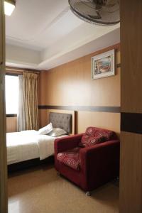 a hotel room with a bed and a red chair at MelInn - Lalitpur in Bākhri Kharka