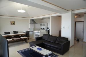 een woonkamer met een zwarte bank en een keuken bij ホワイトヒルズ in Tomigusuku