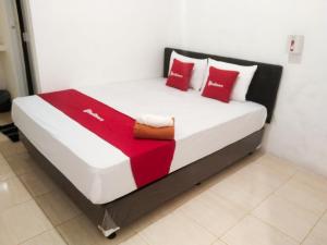 a bed in a room with red and white pillows at RedDoorz near Juwata 3 Airport Tarakan in Karanganyar
