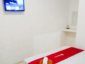 a room with a red blanket and a tv at RedDoorz near Juwata 3 Airport Tarakan in Karanganyar