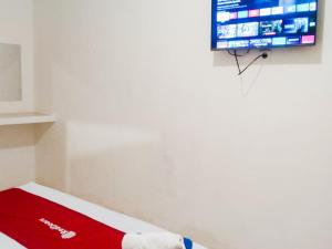 a room with a bed with a tv on a wall at RedDoorz near Juwata 3 Airport Tarakan in Karanganyar +7 photos