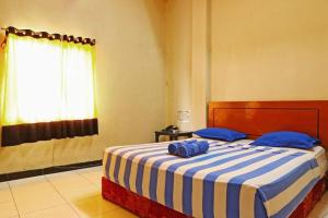 Un dormitorio con una cama con almohadas azules y una ventana. en Residence Hotel Medan, en Medan