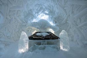 an ice sculpture of a dinosaur sleeping on a bed at IceHotel in Jukkasjärvi