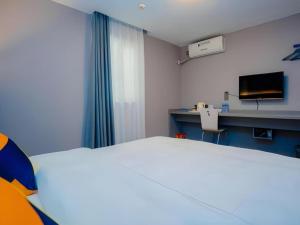 a room with a bed and a desk and a tv at 7 Days Inn Xi'an Railway Station in Xi'an