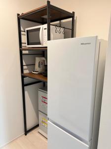 a refrigerator next to a shelf with a microwave at ブレイブベース糸島 in Itoshima