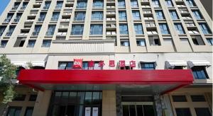 a large building with a red sign in front of it at ibis Wuxi Jiangnan University in Wuxi