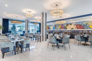 a dining room with tables and chairs and a mural at Cambria Hotel Waco University Riverfront in Waco