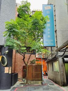 a tree in front of a building with a sign at Fun Stay Inn Hanzhong in Taipei