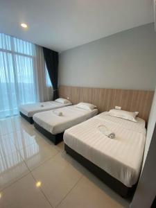 three beds in a hotel room with windows at Stirling Homestay by Evernent in Miri