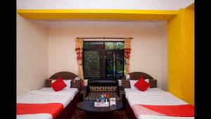 a room with two beds with red pillows and a table at Hotel Green View in Ilām