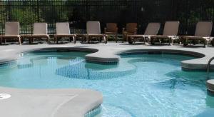 a swimming pool with lounge chairs and chairs in it at Adam's Mark Hotel & Conference Center in Independence