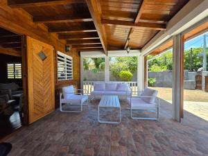 un patio con sillas blancas y una mesa en Chalet Privé avec Piscine 3 Chambres 6 Personnes, en Pointe d'Esny