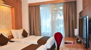 a hotel room with two beds and a television at d'primahotel Mega Kuningan in Jakarta