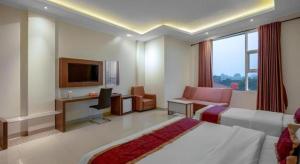 a hotel room with a bed and a desk and a tv at Raffleshom Hotel in Bandung