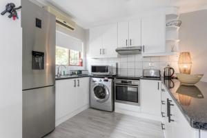a kitchen with white cabinets and a washer and dryer at 39 Kingston in Ballito
