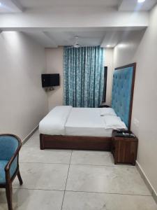Un dormitorio con una cama y una silla y un televisor. en Hotel Galaxy, en Jodhpur