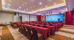 a conference room with red tables and chairs and a screen at Zhuhai Starlight Hotel in Zhuhai