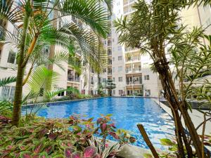 a large swimming pool with palm trees in front of a building at Sudirman Suites by Eazystay in Bandung