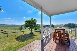 a wooden porch with a table and chairs on a field at Stellaview Estate in Mitchells Flat