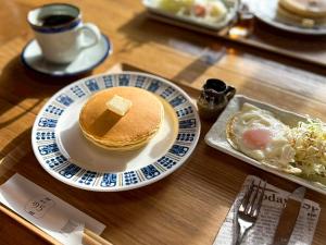 a plate of pancakes with a piece of butter on a table at 江田島宿りNORA Private Vacation Home 