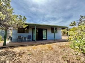 a small blue house with a porch with a table at Beachside Cabin No 2 at Island Beach in Island Beach