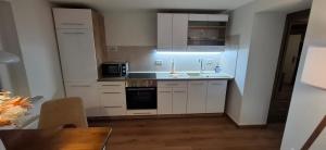 a small kitchen with white cabinets and a sink at bei GRETA 35 in Marl