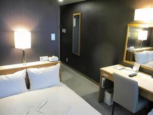 Un dormitorio con una cama, un escritorio y un espejo. en Niigata Keihin Hotel, en Nuttari