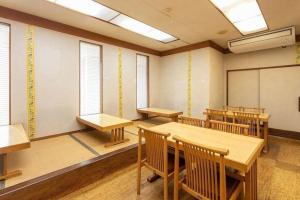 an empty room with tables and chairs in a classroom at Business Hotel Shinkawa Ube in Ube